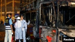 Peruvian police and investigators work next to a burnt bus on a street in Lima, Peru, March 31, 2019.