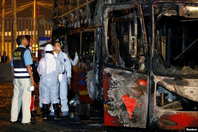 Peruvian police and investigators work next to a burnt bus on a street in Lima, Peru, March 31, 2019.