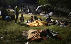 People displaced from their earthquake destroyed homes spend the night outdoors in a grassy area that is part of a hospital in Les Cayes, Haiti, late Saturday, Aug. 14, 2021.