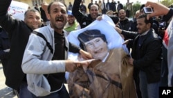 Protesters deface a poster of Libyan leader Moammar Gadhafi in the city of Zawiyah, February 27, 2011