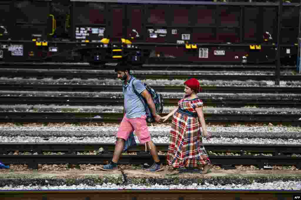 A Syrian migrant and his pregnant wife walk on train tracks towards the town of Gevgelija on the Macedonian-Greek border to catch a train to Serbia and the North European countries, July 27, 2015.