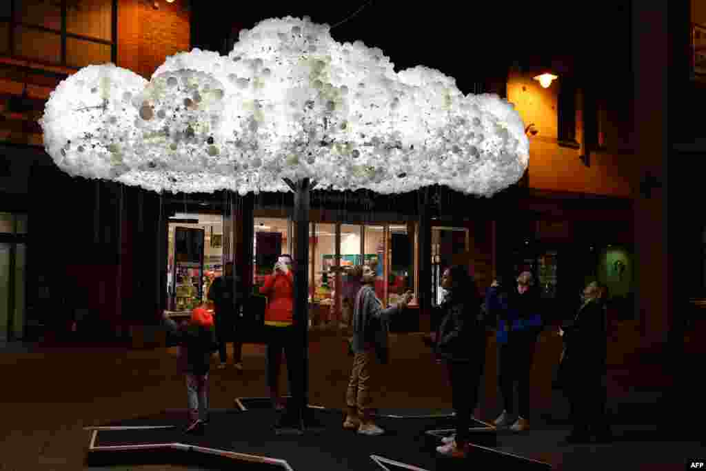 Visitors admire the artwork &#39;Cloud&#39;, formed from 6,000 incandescent light bulbs, during a rehearsal for &#39;Lumiere Durham&#39; light festival in the British city of Durham on November 13, 2019.