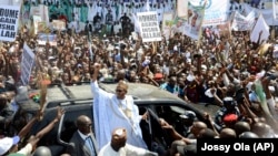 FILE - Nigerian presidential candidate Muhammadu Buhari, center, from the All Progressives Congress party waves to his supporters as he arrives for a party rally in Maiduguri, Feb. 16, 2015.
