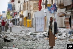 FILE - A Shiite fighter known as a Houthi stands guard in front of buildings destroyed by a Saudi-led airstrike in Sana'a, Sept. 5, 2015.