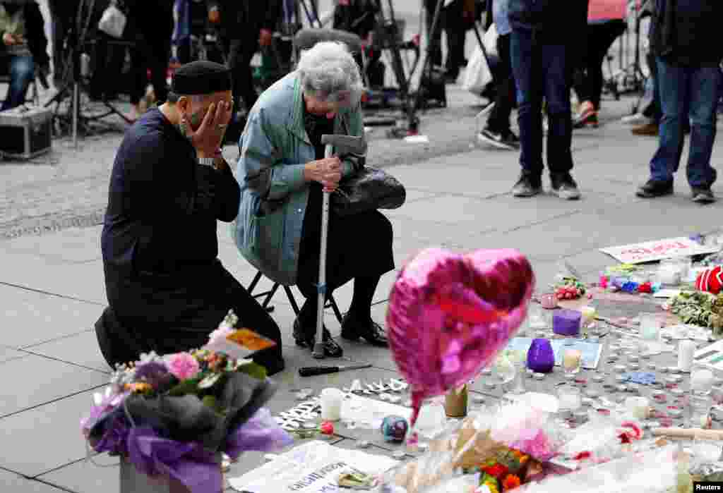 A Jewish woman named Renee Rachel Black and a Muslim man named Sadiq Patel react next to floral tributes for the victims of the concert blast, at St. Ann&#39;s Square in Manchester, Britain.