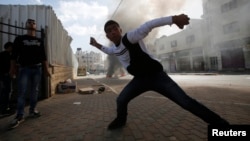 FILE - A young Palestinian protester throws stones at Israeli troops during clashes following an anti-Israel demonstration in solidarity with al-Aqsa mosque, in the West Bank city of Hebron, Nov. 14, 2014.