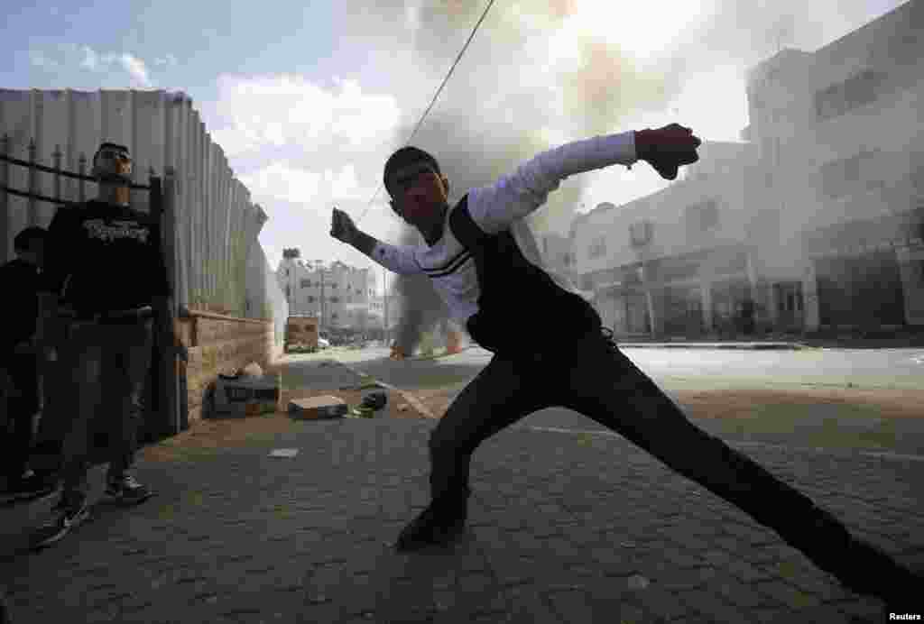 A young Palestinian protester throws stones at Israeli troops during clashes following an anti-Israel demonstration in solidarity with al-Aqsa mosque, in the West Bank city of Hebron, Nov. 14, 2014.