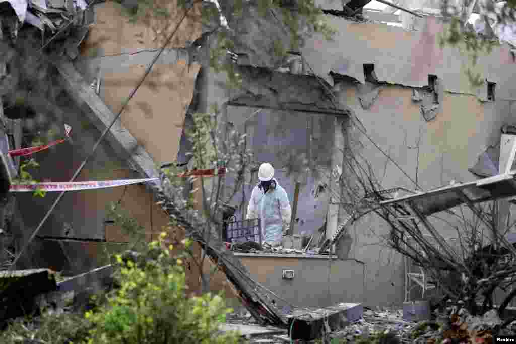 A police sapper inspects a damaged house that was hit by a rocket north of Tel Aviv, Israel.