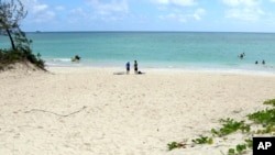 In this May 15, 2019, photo, people stand near the ocean at Kailua Beach Park in Kailua, Hawaii. Stephen Leatherman, known as "Dr. Beach," selected the beach as one of the top U.S. this year. (AP Photo/Caleb Jones)