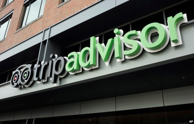 FILE - The company logo for the travel website TripAdvisor hangs at the company's headquarters, Thursday, Nov. 2, 2017, in Needham, Mass. (AP Photo/Steven Senne)