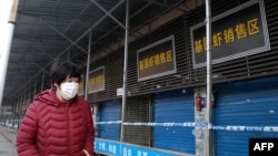 Seorang perempuan melintas di depan pasar makanan laut Huanan yang ditutup setelah seorang pria yang membeli makanan di Kota Wuhan, meninggal karena penyakit infeksi saluran pernafasan, 12 Januari 2020.
