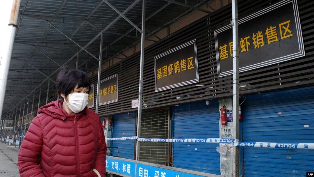 Seorang perempuan melintas di depan pasar makanan laut Huanan yang ditutup setelah seorang pria yang membeli makanan di Kota Wuhan, meninggal karena penyakit infeksi saluran pernafasan, 12 Januari 2020.