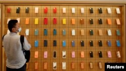 Un hombre se para frente a una pared de fundas de iPhone en la nueva tienda insignia de Apple en su día de apertura en Sanlitun en Beijing, China, el 17 de julio de 2020. 