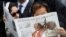 FILE - A woman reads a copy of the Vatican newspaper L'Osservatore Romano as she waits for the canonization ceremony in St Peter's Square at the Vatican, Apr. 27, 2014.
