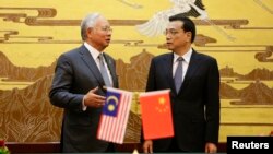 Malaysia's Prime Minister Najib Razak (L) speaks to China's Premier Li Keqiang during a signing ceremony at the Great Hall of the People, in Beijing, May 29, 2014.