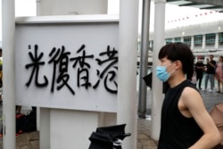 A protester walks past graffiti reading "Restore Hong Kong" during a demonstration in Hong Kong, Saturday, Aug. 3, 2019.