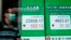 A man wearing face mask walks past a bank electronic board showing the Hong Kong share index at Hong Kong Stock Exchange, May 14, 2020.