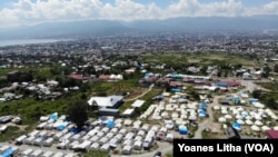 Deretan tenda-tenda yang menjadi tempat tinggal warga terdampak likuifaksi di Balaroa, Palu Barat, Kota Palu Sulawesi Tengah, dengan latar belakang teluk dan Kota Palu, 22 Juli 2019. (Foto: Yoanes Litha/VOA)