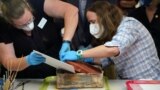 FILE - Kate Ridgeway and Sue Donovan, conservators with the Virginia Department of Historic Resources, remove one of three books found in a time capsule recovered from Confederate General Robert E. Lee's monument in Richmond, Virginia, Dec. 22, 2021. 