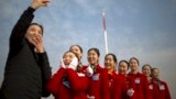 Hospitality staff members react after posing for a selfie during the opening session of China's National People's Congress (NPC) at the Great Hall of the People in Beijing, Monday, March 5, 2018. 