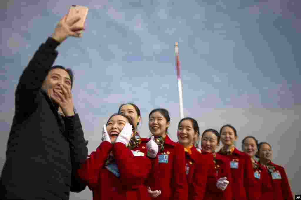Hospitality staff members pose for a selfie during the opening session of China&#39;s National People&#39;s Congress (NPC) at the Great Hall of the People in Beijing.