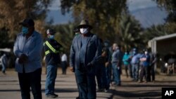 Trabajadores agrícolas esperan en la fila para recibir la vacuna Pfizer-BioNTech para contrarrestar el COVID-19, en Tudor Ranch en Mecca, California, el jueves 21 de enero de 2021.