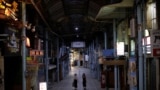 FILE - Passersby wearing protective face masks, amid the COVID-19 pandemic, walk at a shopping arcade in the prefectural capital Naha, on the southern island of Okinawa, Okinawa prefecture, Japan, Oct. 24, 2021.