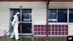 A worker decontaminates radiation from the exterior of Yasawa Kindergarten in Minami-Soma, about 12 miles (20 kilometers) away from the tsunami-crippled Fukushima Dai-ichi nuclear facility, in Fukushima prefecture, northeastern Japan, August 18, 2011