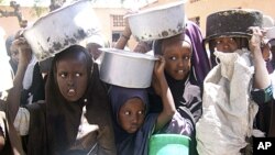 Internally displaced Somali children line up with containers in hand to receive food aid at a food distribution center, in Mogadishu, Somalia.