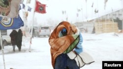 A camper braces against high winds and a blizzard while walking inside the Oceti Sakowin camp as "water protectors" continue to demonstrate against plans to pass the Dakota Access pipeline adjacent to the Standing Rock Sioux Reservation, near Cannon Ball,