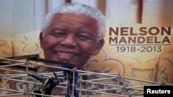 An image of Nelson Mandela is displayed on a digital screen as workers on scaffolding construct a stage ahead of Mandela's national memorial service at First National Bank (FNB) Stadium, also known as Soccer City, in Johannesburg, Dec. 9, 2013.
