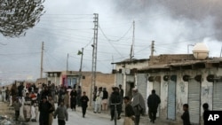 Local residents gather at a road as smoke rise from the site of a bomb blast in a market in Quetta, Pakistan, Feb. 16, 2013.