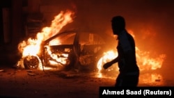 今年巴格​​達平民死亡人數比去​​年增加一倍多。巴格達一名男子看著爆炸後燃燒的汽車， 2013年10月7日。 (資料圖片)
