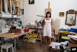 Emmanuelle Prevot, working as restorer of paintings and art creations poses in her painting workshop in Paris, Tuesday, July 21, 2020. Emmanuelle said that she does not wear a mask always while working with chemicals for paintings.