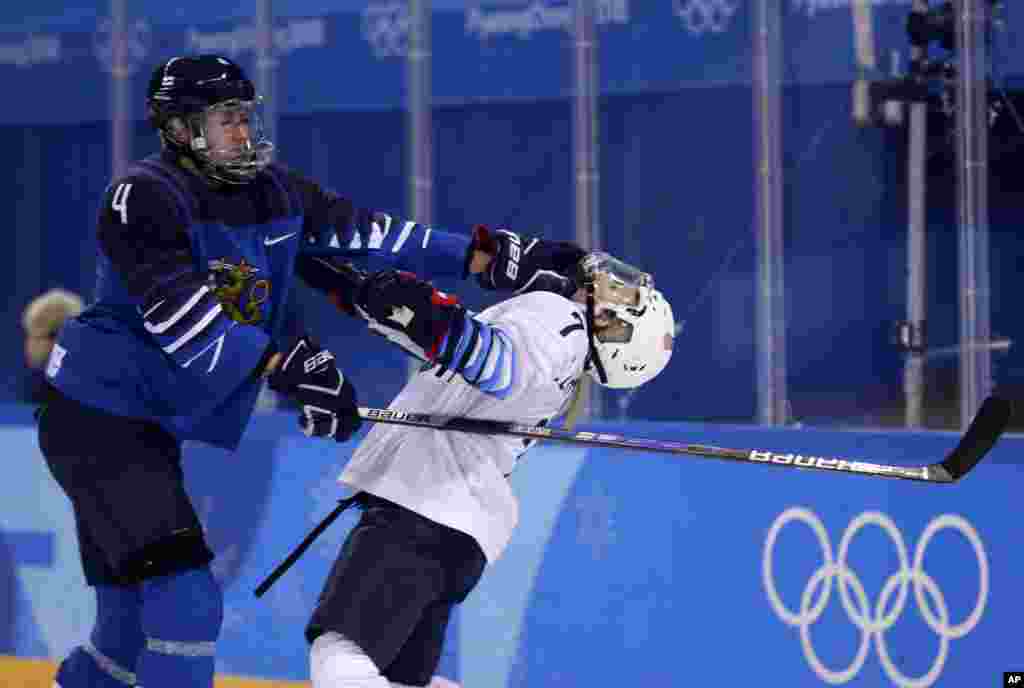 Monique Lamoureux-Morando (7), of the United States, takes a punch from Rosa Lindstedt (4), of Finland, during the second period of the preliminary round of the women&#39;s hockey game at the 2018 Winter Olympics in Gangneung, South Korea.