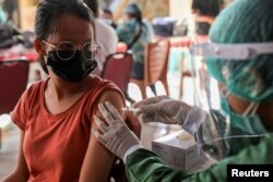 Seorang perempuan divaksinasi COVID-19 dengan vaksin AstraZeneca di Sanur, Bali, 23 Maret 2021. (REUTERS / Nyimas Laula)