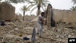 Pakistani earthquake survivor carries a goat among the rubble of collapsed mud houses in the Mashkail area of southwestern Baluchistan province on April 17, 2013.