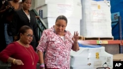 Haiti's Health Minister Florence Duperval Guillaume, left, leads a tour for first lady Sophia Martelly through a warehouse housing a donation of kits to treat chikungunya, in the Cite Soleil slum, in Port-au-Prince, Sept. 10, 2014. 
