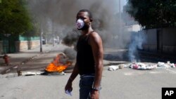 Yon manifestan kap mache tou pre kawotchou kap boule nan lari Pòtoprens pandan jounen grèv jeneral 18 septan 2017 la. Pòtoprens, Ayiti. (Foto: AP/Dieu Nalio Chery)