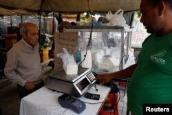 A vendor weighs cheese for a customer at a street market in Caracas, Venezuela, Dec. 19, 2017.