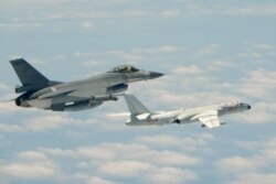 This handout photograph taken and released on May 11, 2018 by Taiwan's Defence Ministry shows a Republic of China (Taiwan) Air Force F-16 fighter aircraft (L) flying alongside a Chinese People's Liberation Army Air Force (PLAAF) H-6K bomber.