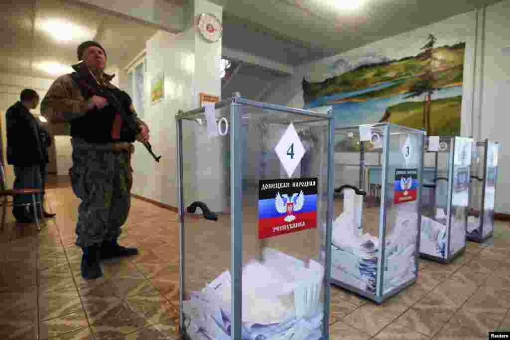 A pro-Russian separatist stands guard during the self-proclaimed Donetsk People's Republic leadership and local parliamentary elections at a polling station in the settlement of Telmanovo, south from Donetsk.