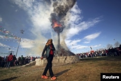 A masked demonstrator walks around a bonfire during a gathering to celebrate the spring festival of Newroz in the Kurdish-dominated southeastern city of Diyarbakir, Turkey, March 21, 2016.