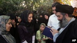 Iranian cleric Hossein Kazemeini Boroujerdi, right, consults with the Quran, as a woman asks for his guidance. (file)