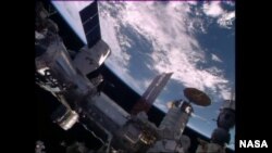 The SpaceX Dragon is seen shortly after it was mated to the Harmony module, April 10, 2016. The Cygnus cargo craft with its circular solar arrays and the Soyuz TMA-19M spacecraft (bottom right) are also seen in this view. (Credit: NASA TV)