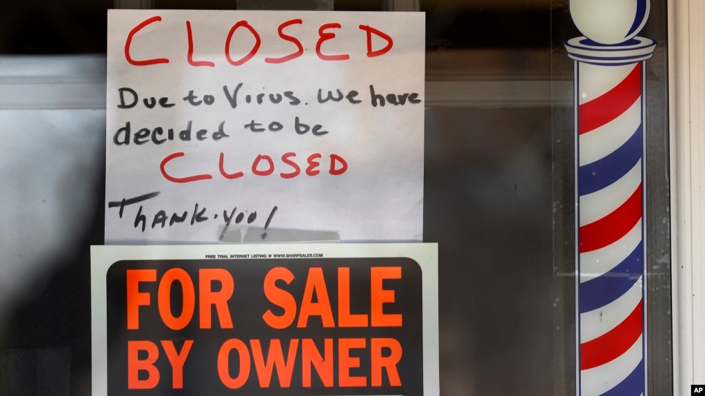 Un cartel de "A la venta por el propietario" y "Cerrado por el virus" es visto en la ventana de un negocio en Grosse Pointe Woods, Michigan, el 2 de abril de 2020.