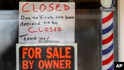 Un cartel de "A la venta por el propietario" y "Cerrado por el virus" es visto en la ventana de un negocio en Grosse Pointe Woods, Michigan, el 2 de abril de 2020.