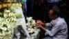 A Bangladeshi social activist lights a candle on floral arrangement that he placed on a road block leading to the Holey Artisan Bakery, the scene of a fatal attack and siege, in Dhaka on July 3, 2016.