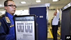 Transportation Security Administration screener Marlon Tejada, left, watches as Randy Parsons, TSA acting Federal Security Director, right, goes through a full body X-ray scanner for a security screening, 22 Nov. 2010