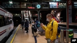 Commuters wearing face masks to protect against coronavirus at the platform of Atocha train station in Madrid, Spain, Monday, April 13, 2020. Spain is re-starting some business activity after locking down the nation to fight the spread of COVID-19. (AP Photo/Bernat Armangue)